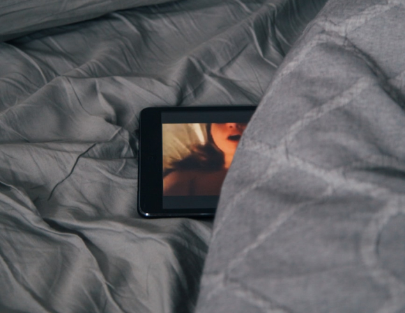 black Android smartphone on gray bed sheet