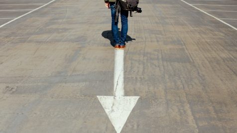 person standing on arrow sign on road