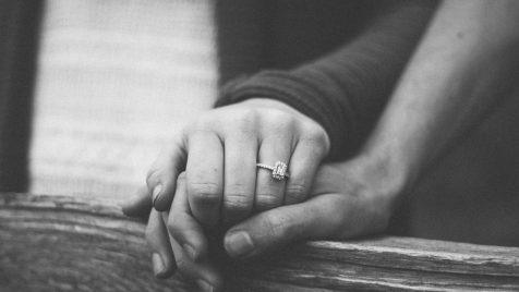 a couple holding hands with a wedding ring visible