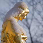 A golden statue of a woman with a book in her hands